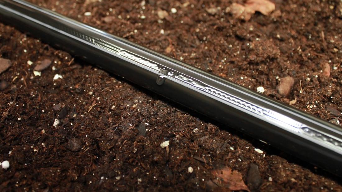 Close-up image of Greener Drip's eco-friendly drip tape placed on soil.